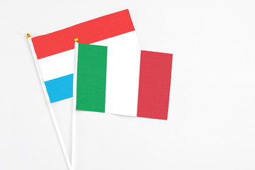 Italy and Luxembourg stick flags on white background. High quality fabric, miniature national flag. Peaceful global concept.White floor for copy space.