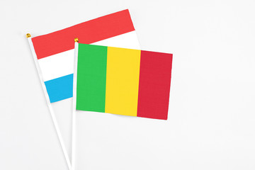 Mali and Luxembourg stick flags on white background. High quality fabric, miniature national flag. Peaceful global concept.White floor for copy space.