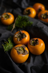 Ripe orange persimmon fruit on a dark gray background. Vegetables. 