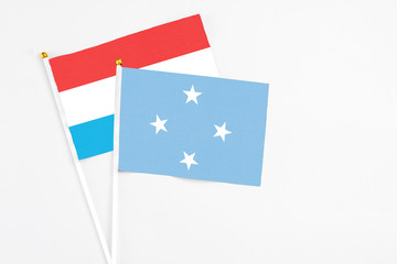 Micronesia and Luxembourg stick flags on white background. High quality fabric, miniature national flag. Peaceful global concept.White floor for copy space.