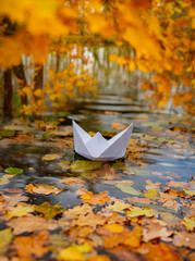 paper boat on an autumn river close up