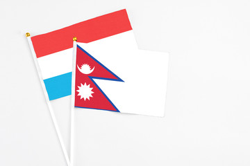 Nepal and Luxembourg stick flags on white background. High quality fabric, miniature national flag. Peaceful global concept.White floor for copy space.