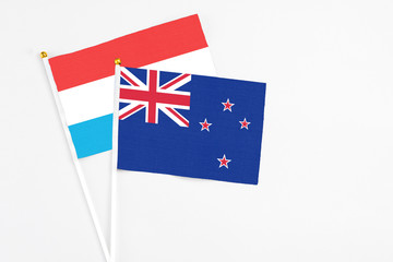 New Zealand and Luxembourg stick flags on white background. High quality fabric, miniature national flag. Peaceful global concept.White floor for copy space.