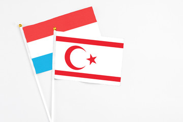 Northern Cyprus and Luxembourg stick flags on white background. High quality fabric, miniature national flag. Peaceful global concept.White floor for copy space.