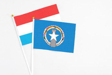 Northern Mariana Islands and Luxembourg stick flags on white background. High quality fabric, miniature national flag. Peaceful global concept.White floor for copy space.