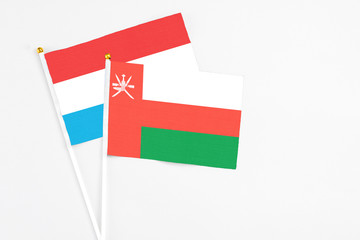 Oman and Luxembourg stick flags on white background. High quality fabric, miniature national flag. Peaceful global concept.White floor for copy space.