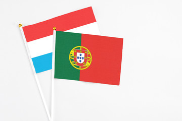 Portugal and Luxembourg stick flags on white background. High quality fabric, miniature national flag. Peaceful global concept.White floor for copy space.