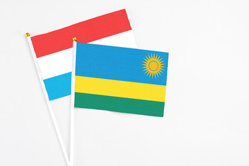 Rwanda and Luxembourg stick flags on white background. High quality fabric, miniature national flag. Peaceful global concept.White floor for copy space.