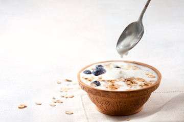 Homemade yogurt with granola and berries in a ceramic bowl on a light background. Concept healthy breakfast.