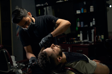 Attractive barber doing a haircut for client with scissors