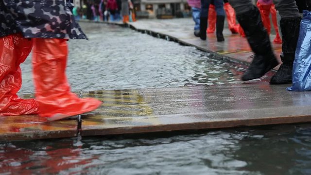 People with plastic gaiters or with boots on the walkway during the flood in Venice in Italy