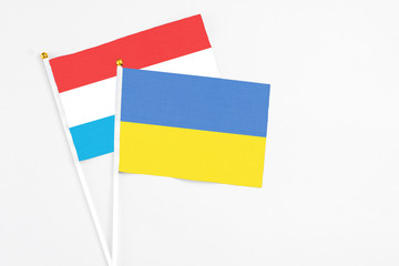 Ukraine and Luxembourg stick flags on white background. High quality fabric, miniature national flag. Peaceful global concept.White floor for copy space.