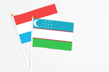 Uzbekistan and Luxembourg stick flags on white background. High quality fabric, miniature national flag. Peaceful global concept.White floor for copy space.