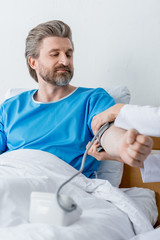 Fototapeta premium cropped view of doctor measuring blood pressure of patient in hospital