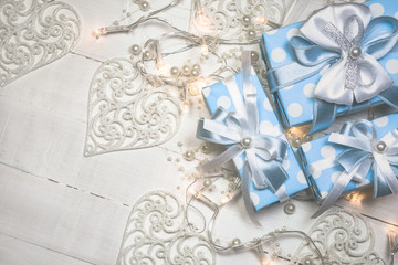Blue gift boxes and lights with pearls on white wooden background