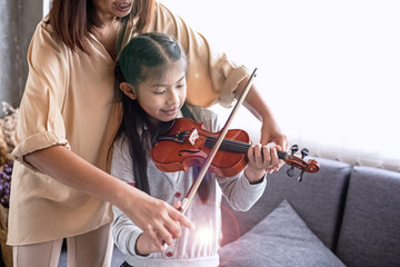 Teacher teaching little girl for playing violin music class,at studio music room,with happy feeling,blurry light aorund,Lvns flare effect