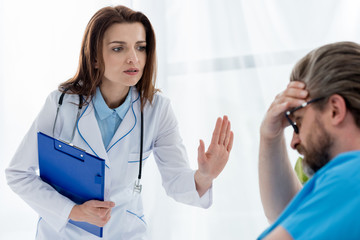 doctor in white coat calming down sad patient in hospital © LIGHTFIELD STUDIOS