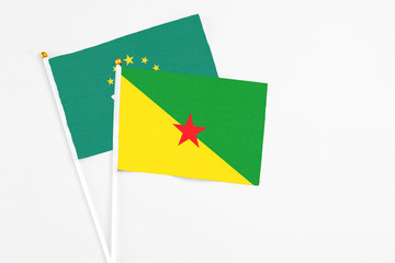 French Guiana and Macao stick flags on white background. High quality fabric, miniature national flag. Peaceful global concept.White floor for copy space.
