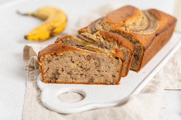 Homemade delicious banana cake with walnuts and cinnamon on white concrete background. Side view, close up. Bakery, recipe concept. Close up. Selective focus