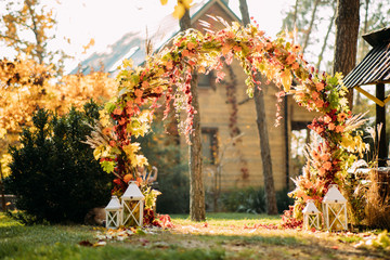 Wedding arch is on the background of autumn trees and house.