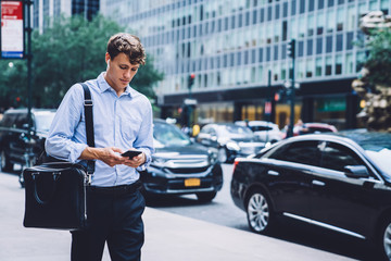 Male employee messaging on phone walking down street