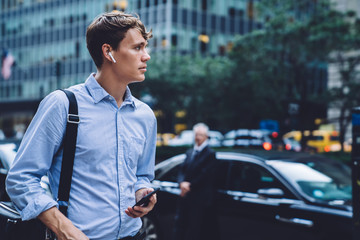 Side view of man walking with phone in hand outdoors