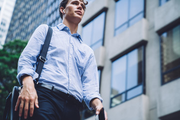 Handsome businessman holding bag talking on mobile while walking on street