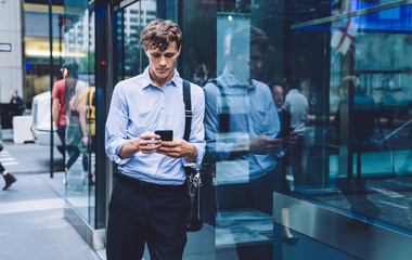 Intelligent man lawyer with typing text message during work break in financial district connected to 4g on cellphone for surfing websites, Caucasian employer searching information on smartphone