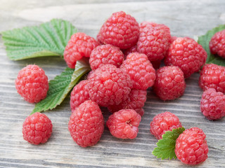Composition with food. handful of fresh raspberries with green leaves laid out on a wooden background