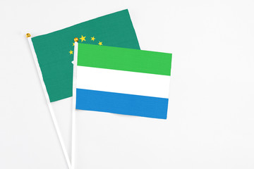 Sierra Leone and Macao stick flags on white background. High quality fabric, miniature national flag. Peaceful global concept.White floor for copy space.