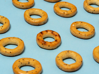 Bread bagels laid out on a blue background. One of them stands out among the rest.