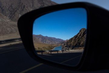 Russia. Mountain Altai. Reflection of the Chui tract in the side mirror of the car near the village...