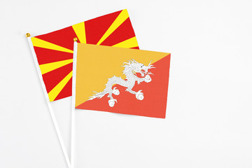 Bhutan and Macedonia stick flags on white background. High quality fabric, miniature national flag. Peaceful global concept.White floor for copy space.