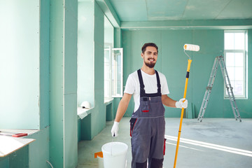 Bearded painter construction worker on a construction site. - obrazy, fototapety, plakaty