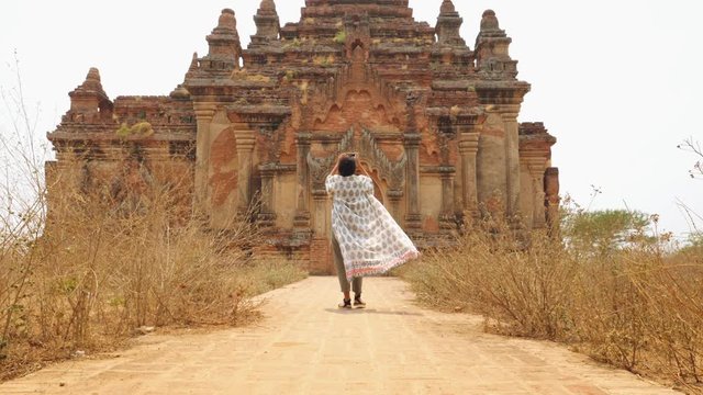Young Tourist Woman Waling to Old Traditional Burmese Temple and Making Photos on Camera. Travel Adventure Lifestyle Vacation Concept. 4K Slowmotion Steadycam Follow Me Footage. Bagan, Myanmar.