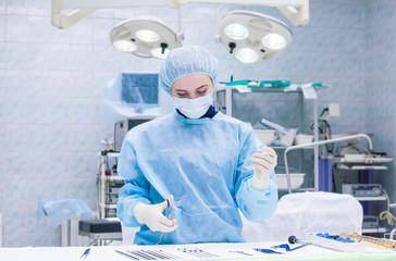 Women, female surgeon cuts a thread in the operating room. Resuscitator doctor in emergency room, near medical steel devices