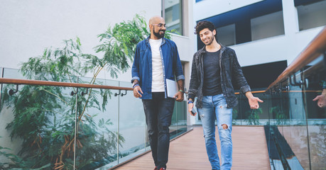 Chatting adult men strolling on terrace