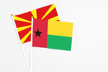 Guinea Bissau and Macedonia stick flags on white background. High quality fabric, miniature national flag. Peaceful global concept.White floor for copy space.