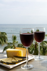 Red wine served in glasses with spanish cheese in lounge bar with sea view and palm trees