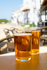 Cold amber color light spanish beer served in glass in outdoor cafe in town on sand, El Rocio in Andalusia, Spain