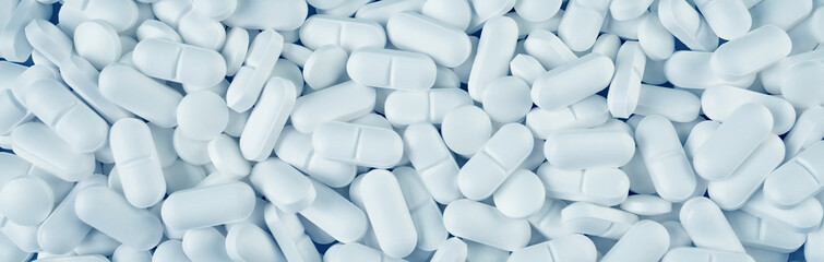 Fototapeta White pills spilled on blue wooden background obraz