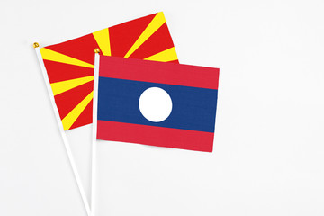 Laos and Macedonia stick flags on white background. High quality fabric, miniature national flag. Peaceful global concept.White floor for copy space.