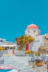 Obraz premium Typical Greek white church and taverna tables in Mykonos town, Greece