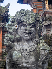 Temple with statues covered with moss on the island of Bali