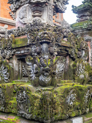 Temple with statues covered with moss on the island of Bali