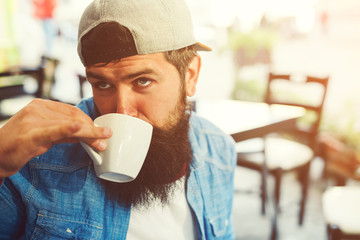 Funny hipster guy drinks coffee. Stylish bearded man at cafeteria outdoors. People, lifestyle and...