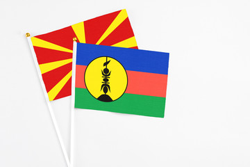 New Caledonia and Macedonia stick flags on white background. High quality fabric, miniature national flag. Peaceful global concept.White floor for copy space.