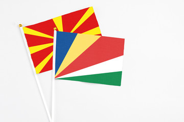 Seychelles and Macedonia stick flags on white background. High quality fabric, miniature national flag. Peaceful global concept.White floor for copy space.