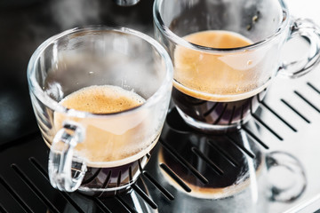 two cups of freshly brewed coffee in the coffee machine