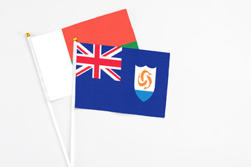 Anguilla and Madagascar stick flags on white background. High quality fabric, miniature national flag. Peaceful global concept.White floor for copy space.